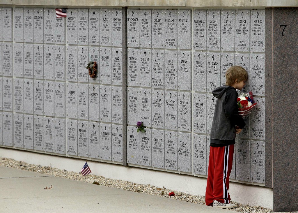 Charles Kosa III rests his head against the columbarium of his grandfather, Vietnam veteran Charles Kosa Sr., on Veterans Day at the Massachusetts National Cemetery in Buzzards Bay, Massachusetts. (Stephan Savoia/Associated Press)